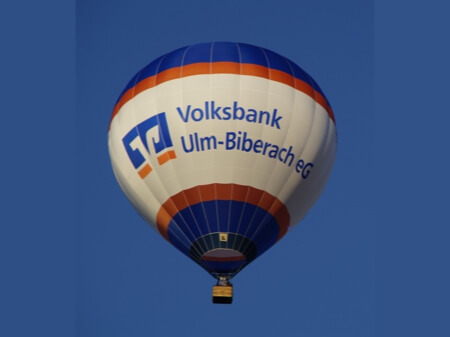 Fotka horkovzdušného balónu vyrobeného v barvách společnosti Volksbank s jejím logem
