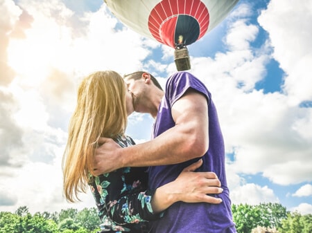 Fotka zasnoubeného páru s horkovzdušným balónem v pozadí